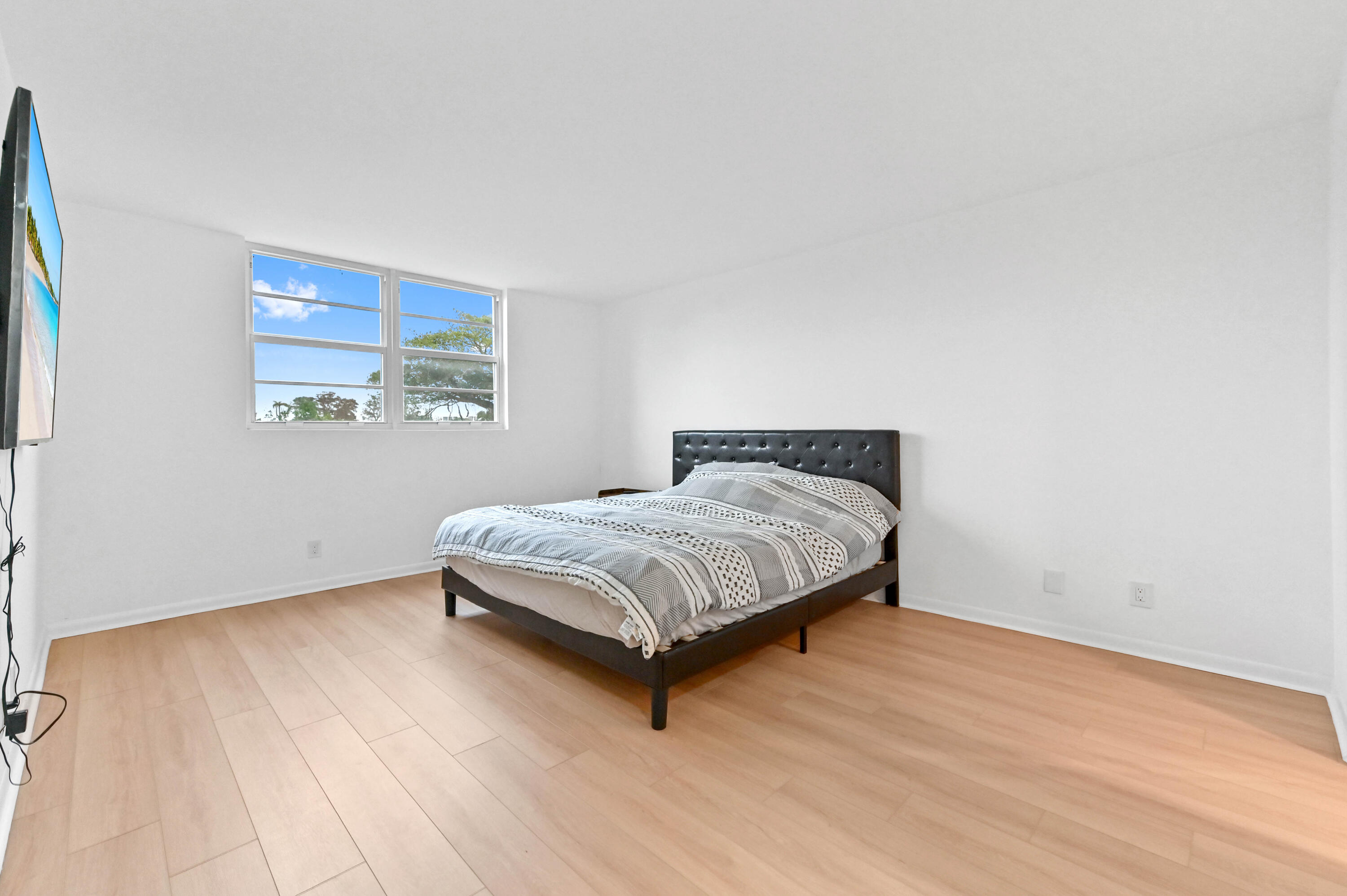 5700 Northwest 2nd Avenue, Unit 211 Boca Raton, FL 33487 - Photo 17 of 29 a bedroom with a bed and wooden floor