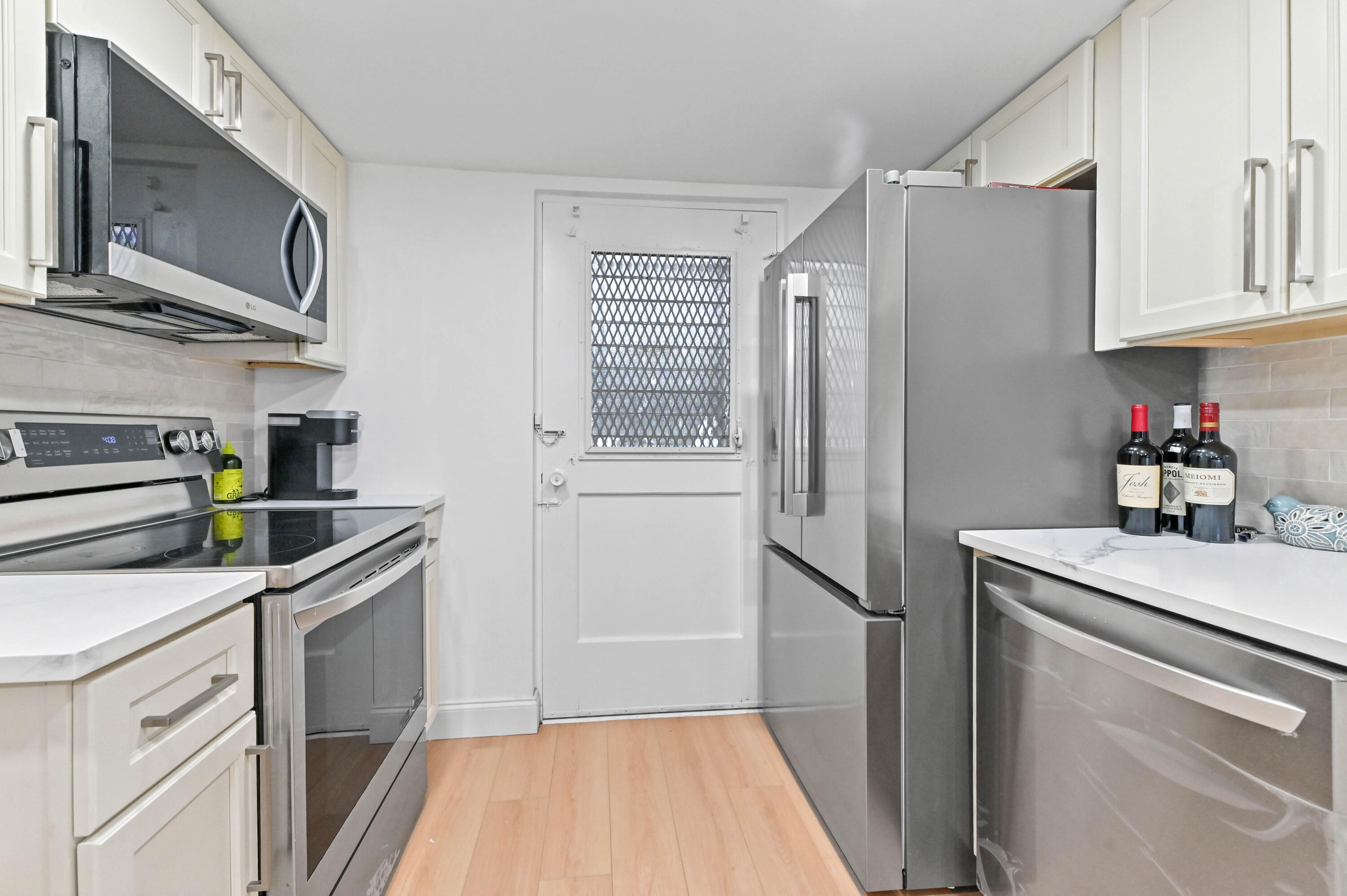 5700 Northwest 2nd Avenue, Unit 211 Boca Raton, FL 33487 - Photo 6 of 29 a kitchen with stainless steel appliances granite countertop a refrigerator a stove a sink and dishwasher with wooden floor