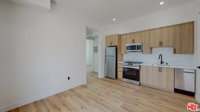 a kitchen with cabinets wooden floor and stainless steel appliances