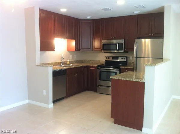 a kitchen with stainless steel appliances granite countertop a stove a sink a refrigerator a microwave and cabinets