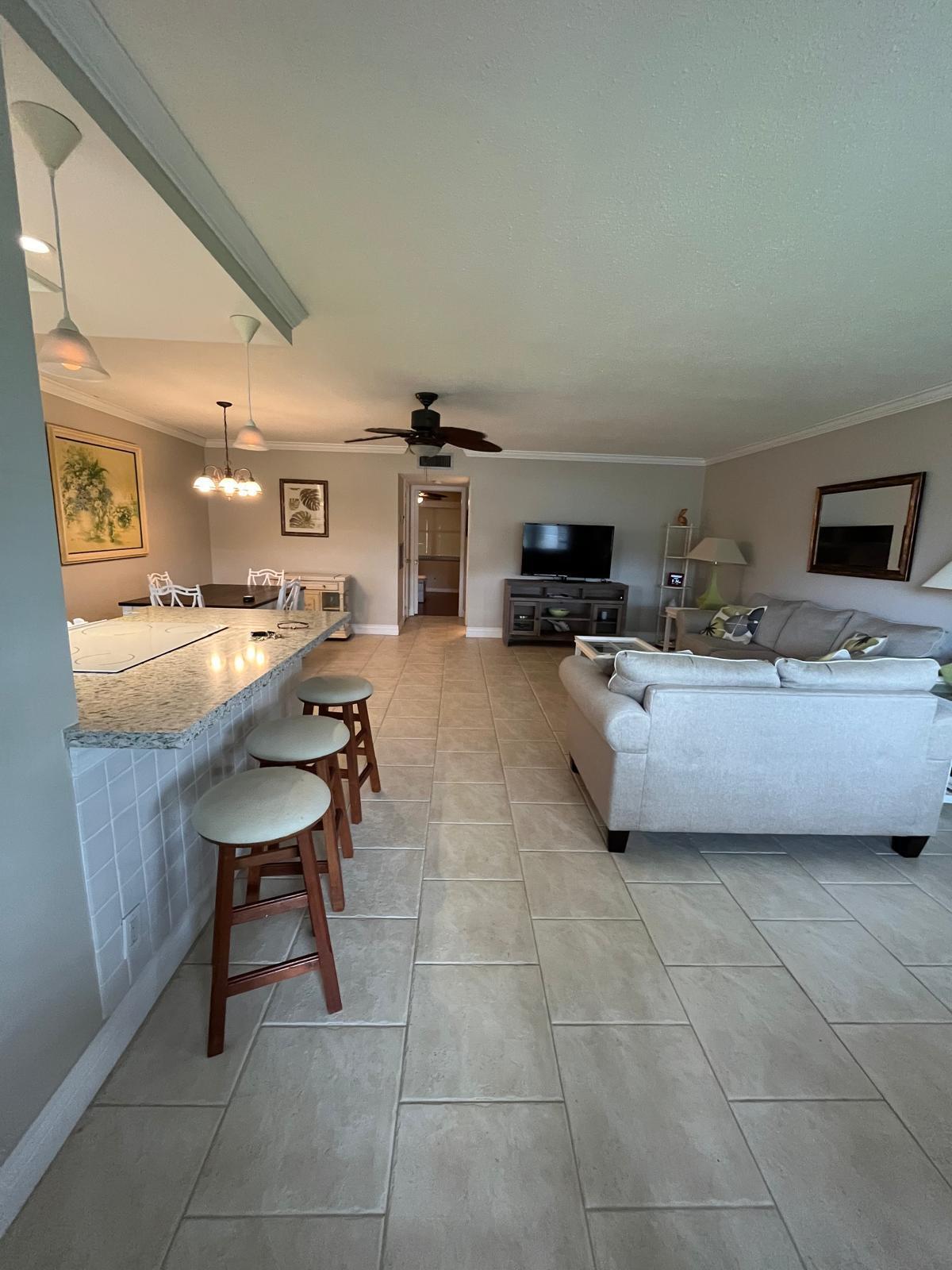 515 High Point, Unit C Delray Beach, FL 33445 - Photo 4 of 23 a living room with furniture a flat screen tv and kitchen view