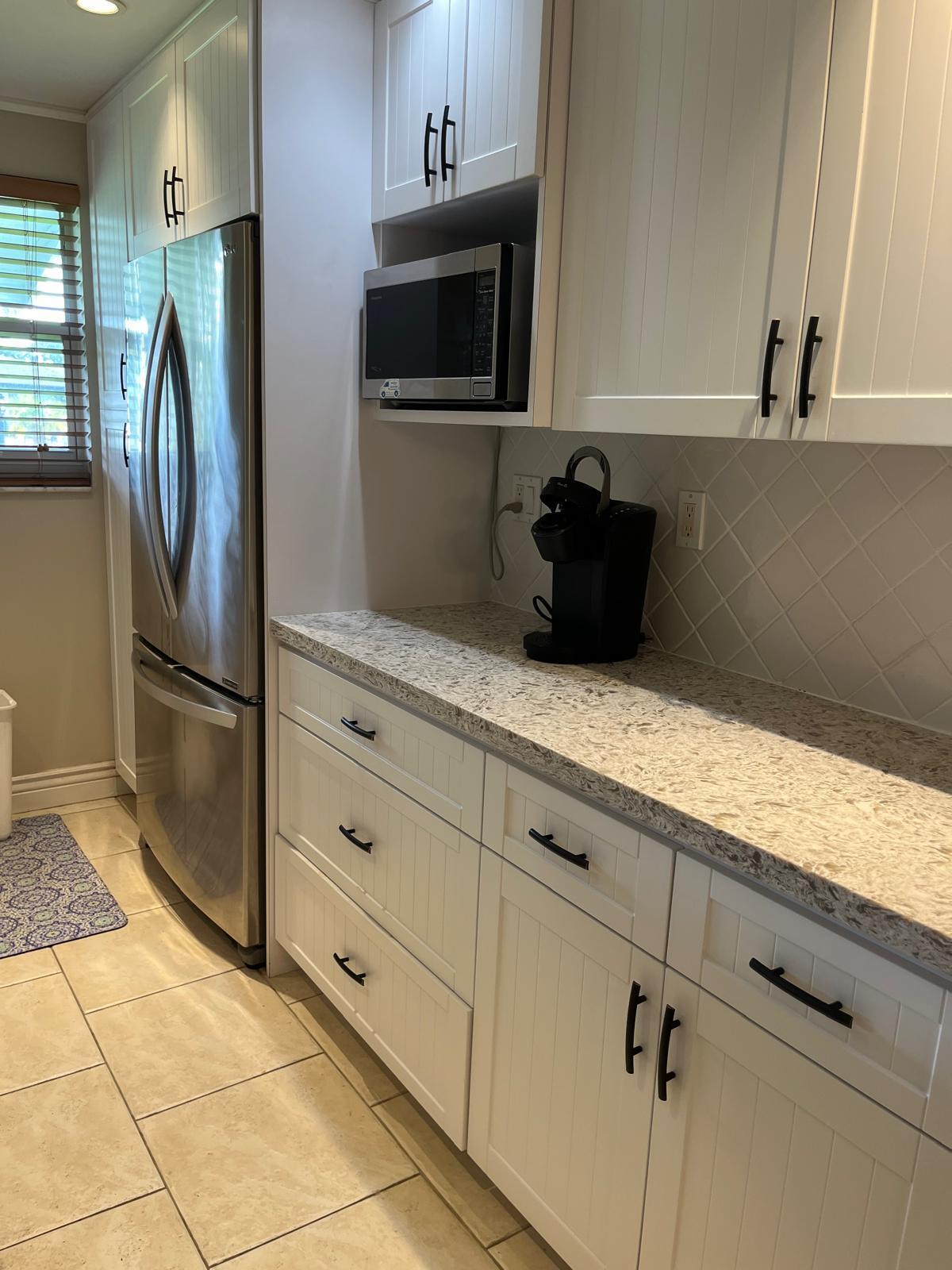 515 High Point, Unit C Delray Beach, FL 33445 - Photo 5 of 23 a kitchen with granite countertop white cabinets and stainless steel appliances