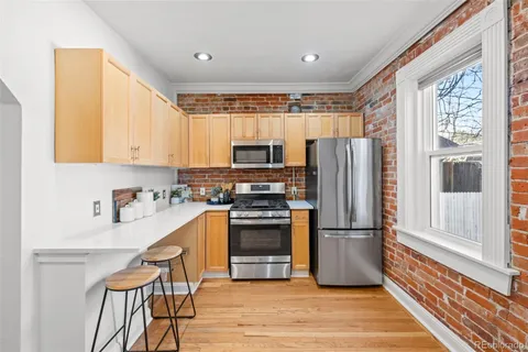 a kitchen with a refrigerator stove and wooden floor