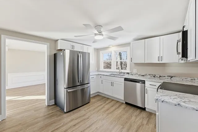 a kitchen with granite countertop stainless steel appliances a refrigerator cabinets and wooden floor