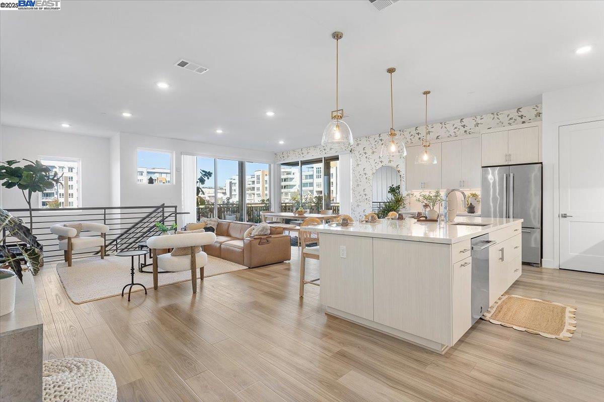 a kitchen with stainless steel appliances kitchen island granite countertop a table chairs stove and white cabinets