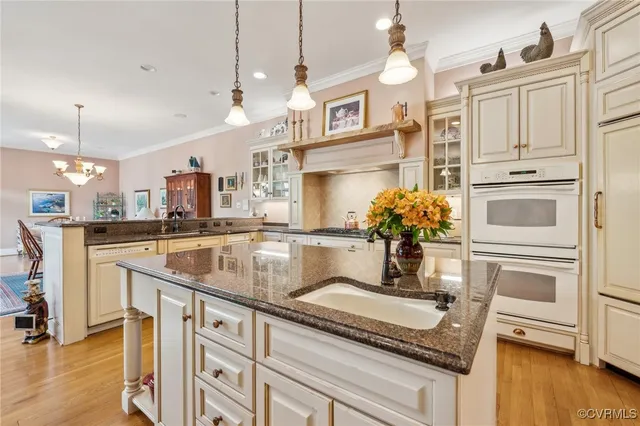 a kitchen with stainless steel appliances granite countertop a sink a stove and a wooden floor