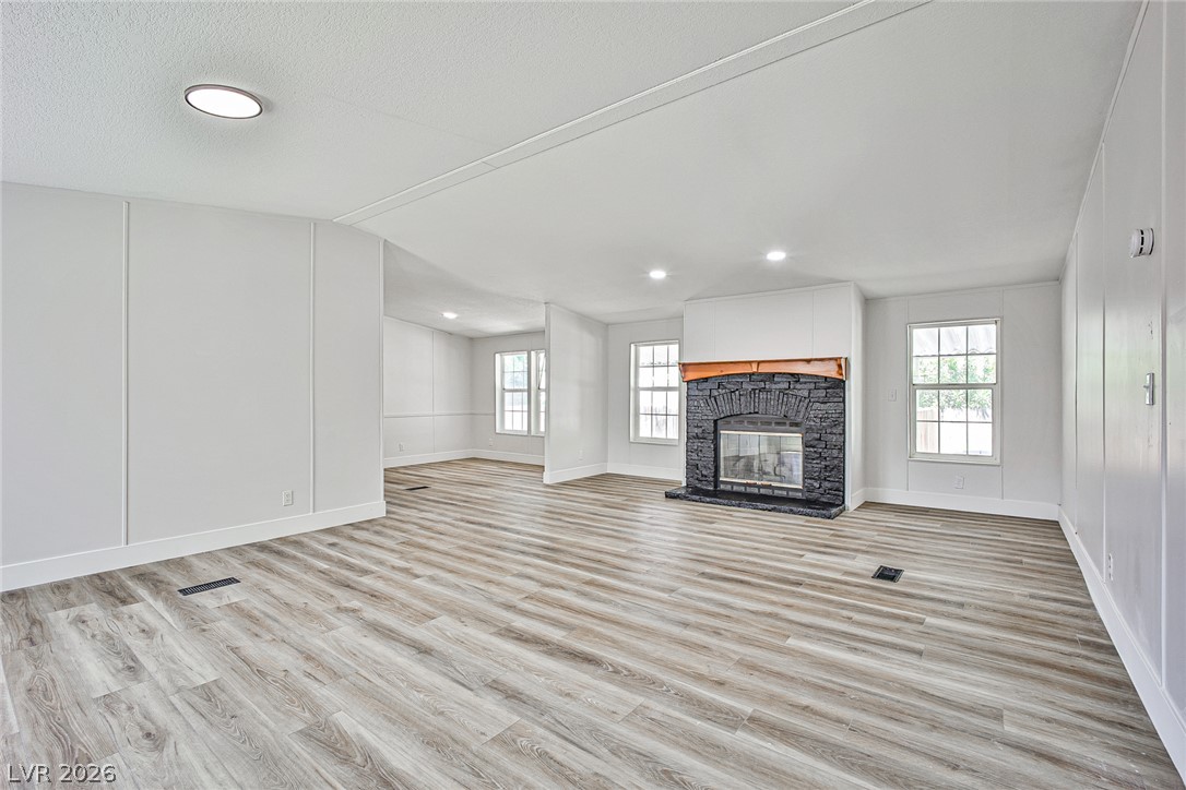 273 Aztec Lane Henderson, NV 89015 - Photo 7 of 28 A well-lit, generous living area showcases a stone fireplace and appealing plank flooring.