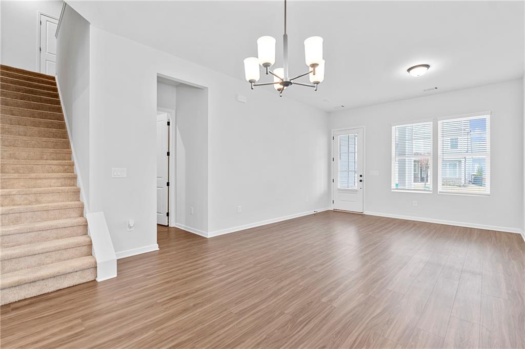 3699 Annsbury Court Lilburn, GA 30047 - Photo 8 of 45 an empty room with wooden floor chandelier and windows
