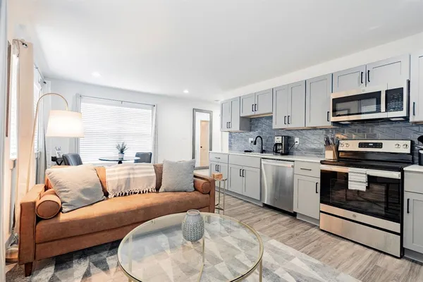 a view of kitchen with stainless steel appliances granite countertop a stove a sink and a microwave