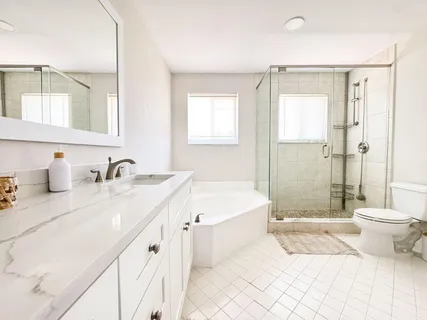 a bathroom with a double vanity sink toilet mirror and bathtub