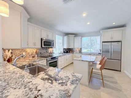 a kitchen with stainless steel appliances granite countertop a stove top oven a sink dishwasher a dining table and chairs with wooden floor