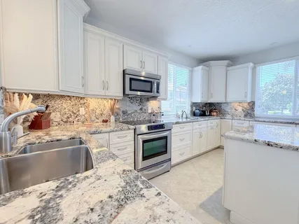 a kitchen with granite countertop a sink a counter top space appliances and cabinets