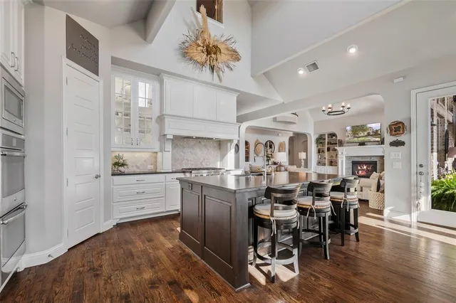 a kitchen with stainless steel appliances kitchen island granite countertop a table chairs and a refrigerator