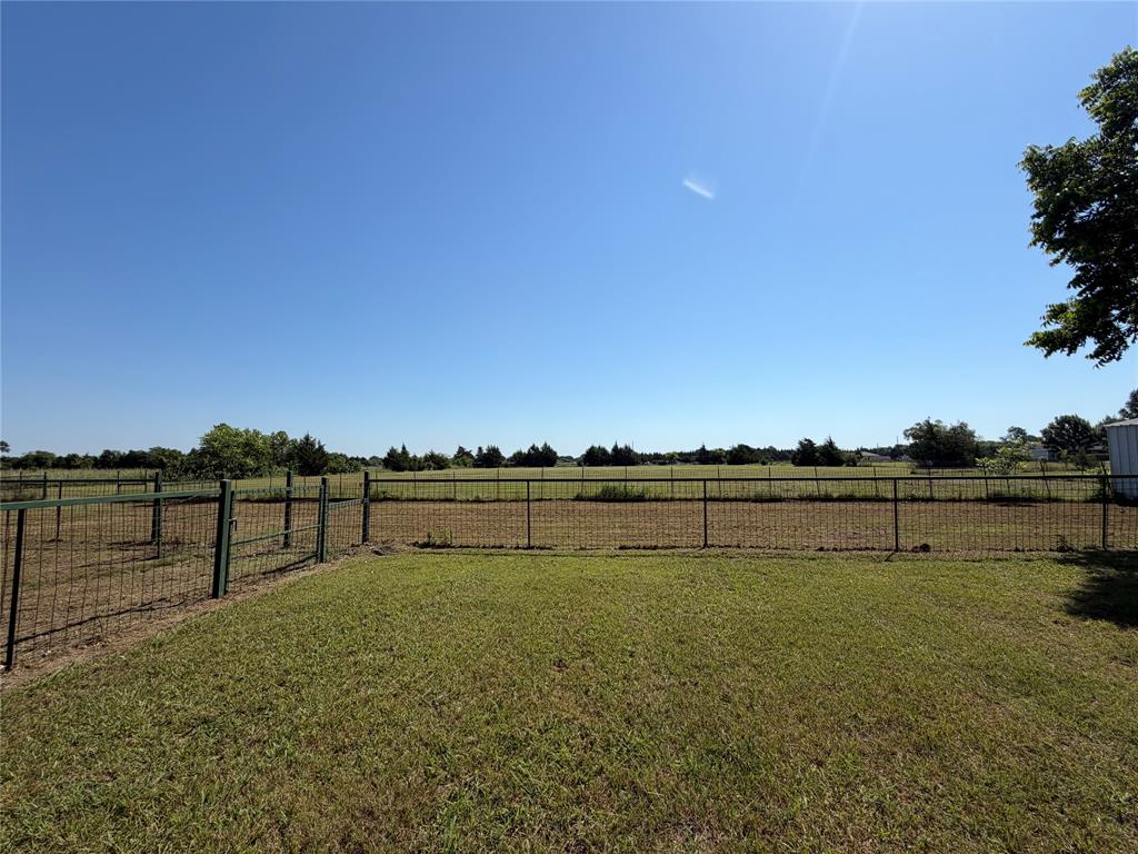 330 South Goode Road Wilmer, TX 75172 - Photo 32 of 37 Expansive fenced yard with a gate, featuring a grass lawn and a metal storage shed