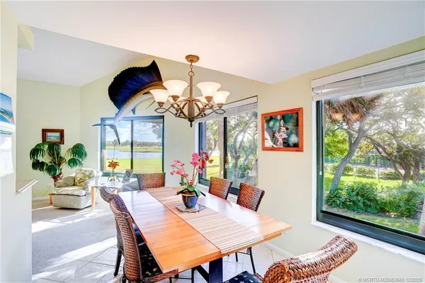 a view of a dining room with furniture a chandelier and large windows