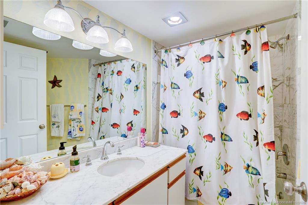 233 Northeast Edgewater Drive, Unit 204 Stuart, FL 34996 - Photo 40 of 56 a bathroom with a sink a mirror and shower curtain