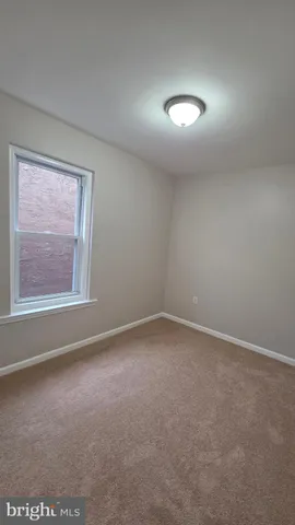 a view of an empty room with closet and a window