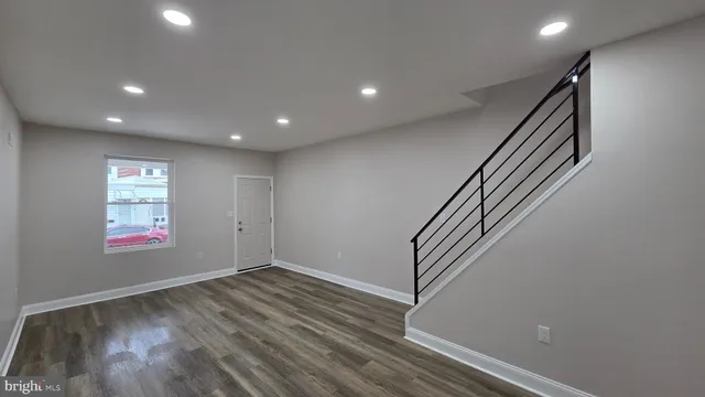 an entryway in hall with wooden floor and stairs