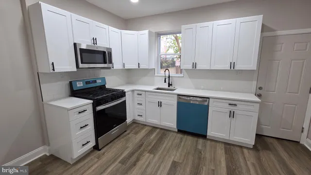a kitchen with white cabinets appliances a sink and a window