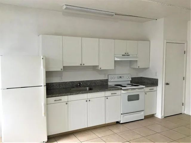 a kitchen with granite countertop white cabinets and white appliances