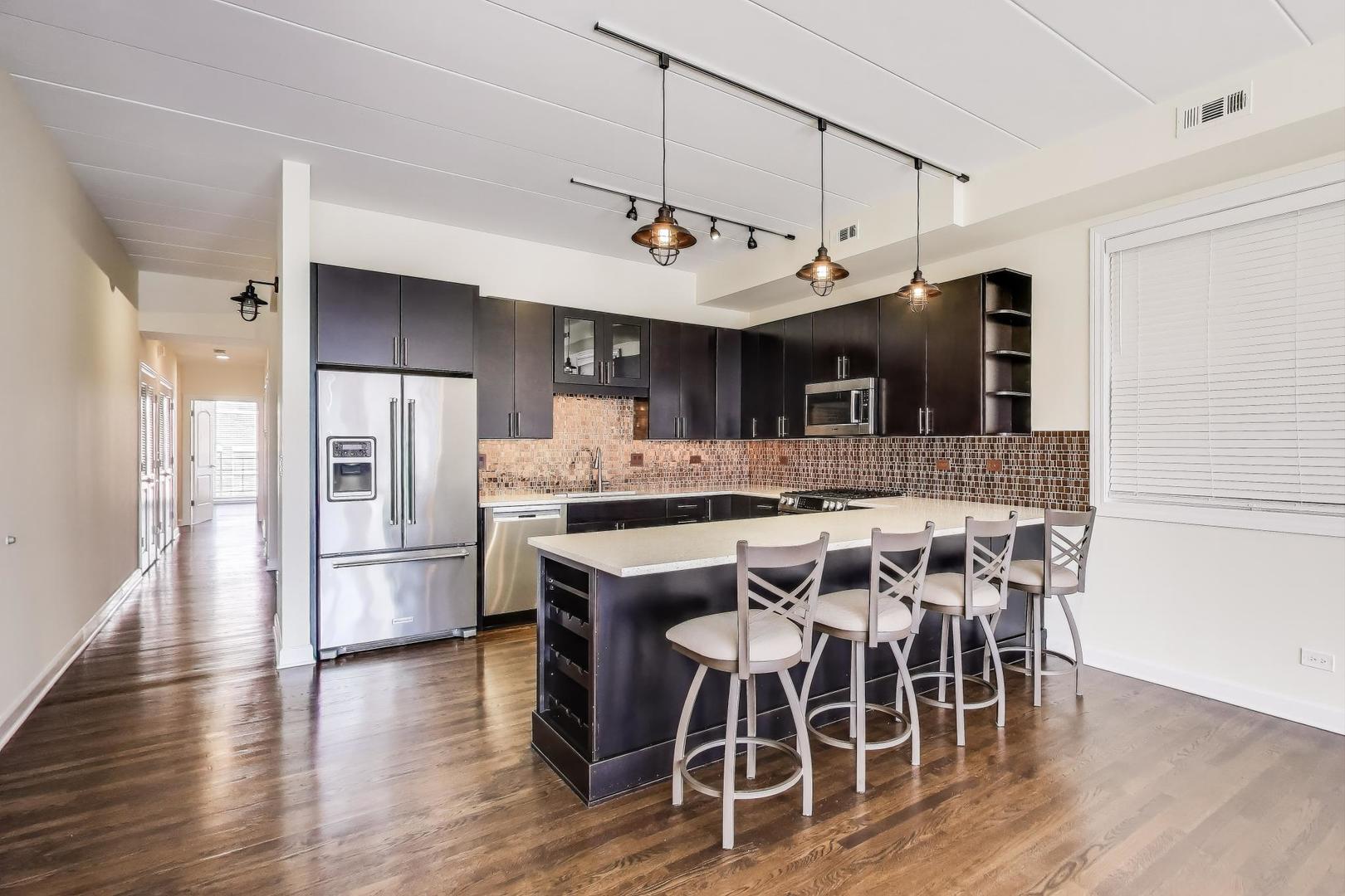 1332 West Madison Street, Unit 4E Chicago, IL 60607 - Photo 4 of 12 a kitchen with stainless steel appliances a table chairs refrigerator and microwave