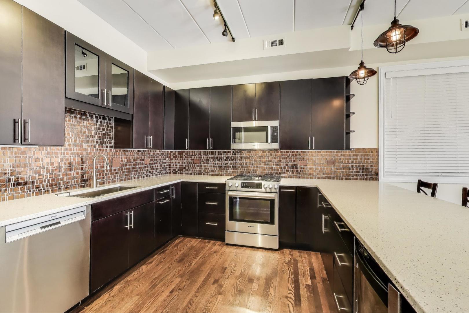 1332 West Madison Street, Unit 4E Chicago, IL 60607 - Photo 5 of 12 a kitchen with stainless steel appliances granite countertop a sink and stove top oven