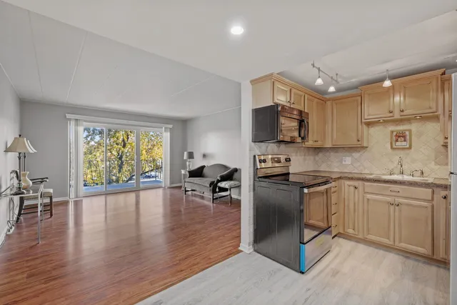 a kitchen with stainless steel appliances granite countertop a stove top oven a sink dishwasher a dining table and chairs with wooden floor