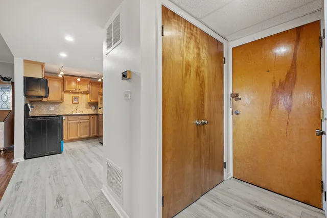 a view of a hallway with wooden floor and a kitchen