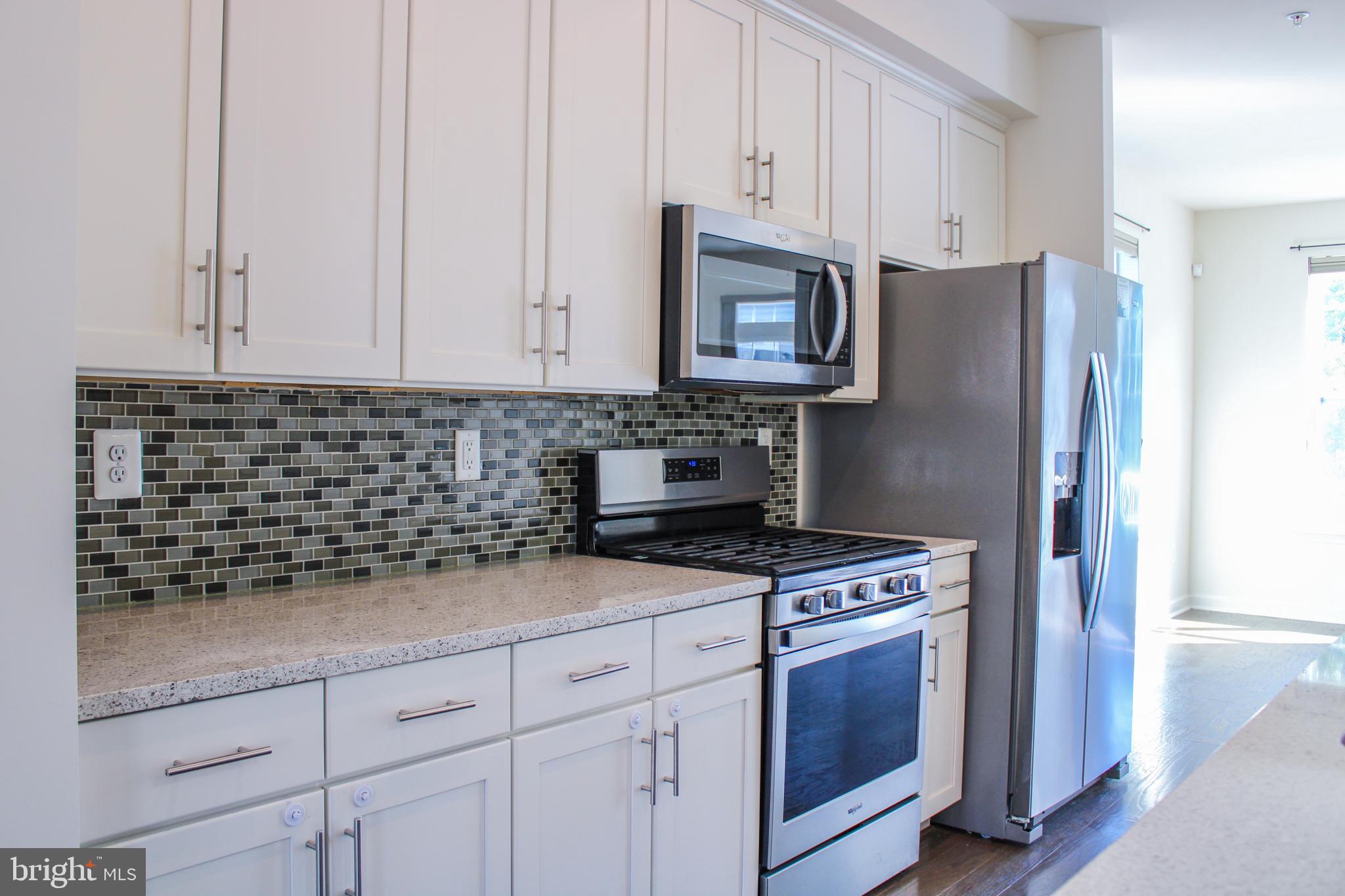 9914 Wood Edge Way Lanham, MD 20706 - Photo 30 of 67 a kitchen with granite countertop white cabinets and stainless steel appliances