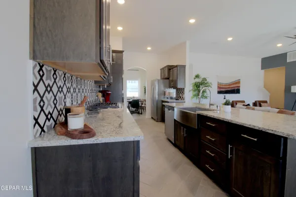 a kitchen with stainless steel appliances granite countertop a table chairs and a refrigerator