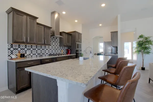a kitchen with stainless steel appliances kitchen island granite countertop a sink and a refrigerator