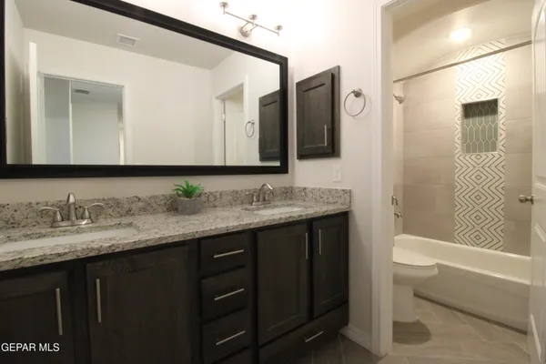 a bathroom with a granite countertop sink double vanity and mirror