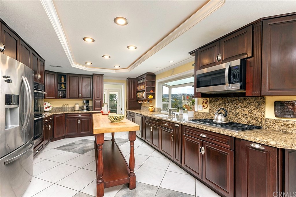 23965 Leeward Drive Dana Point, CA 92629 - Photo 7 of 27 a large kitchen with stainless steel appliances wooden cabinets a stove top oven a sink and dishwasher