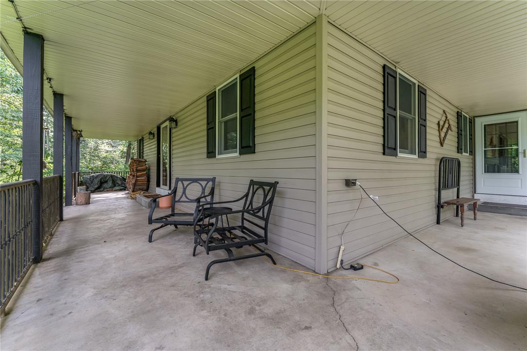 465 Raubsville Road Easton, PA 18042 - Photo 6 of 60 An inviting covered porch offers serene outdoor living amidst a wooded backdrop.
