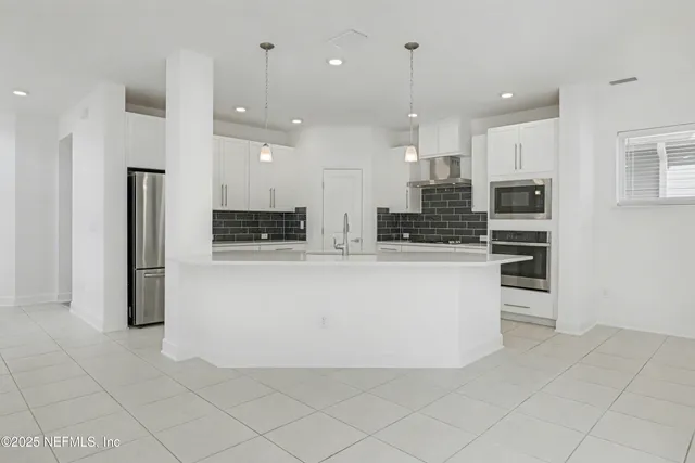 a large kitchen with kitchen island a stove a refrigerator a sink and a oven