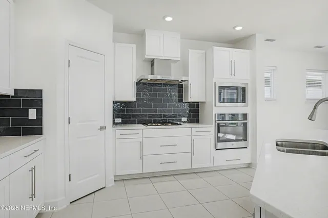 a kitchen with white cabinets and appliances