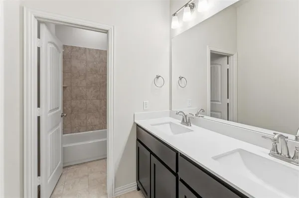 a bathroom with a tub sink double vanity and shower