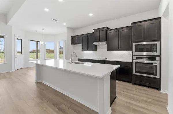 a kitchen with stainless steel appliances kitchen island granite countertop a refrigerator a stove and a wooden floors