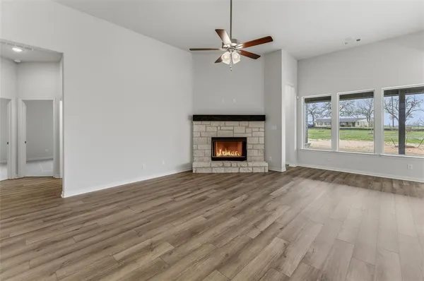 a view of an empty room with wooden floor fireplace and a window