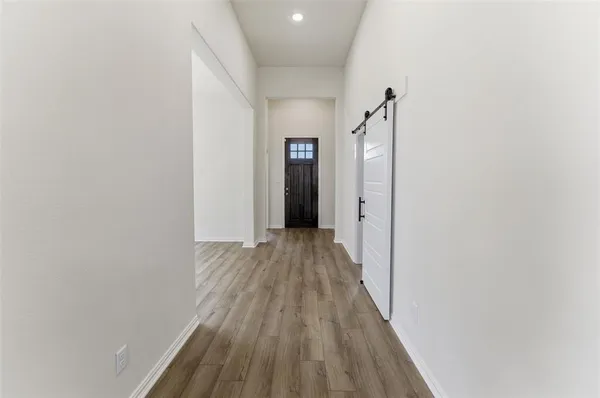 a view of a hallway with wooden floor and a bathroom
