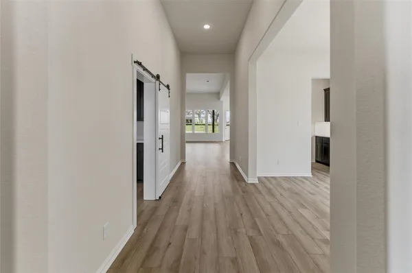 a view of a hallway with wooden floor and a bathroom