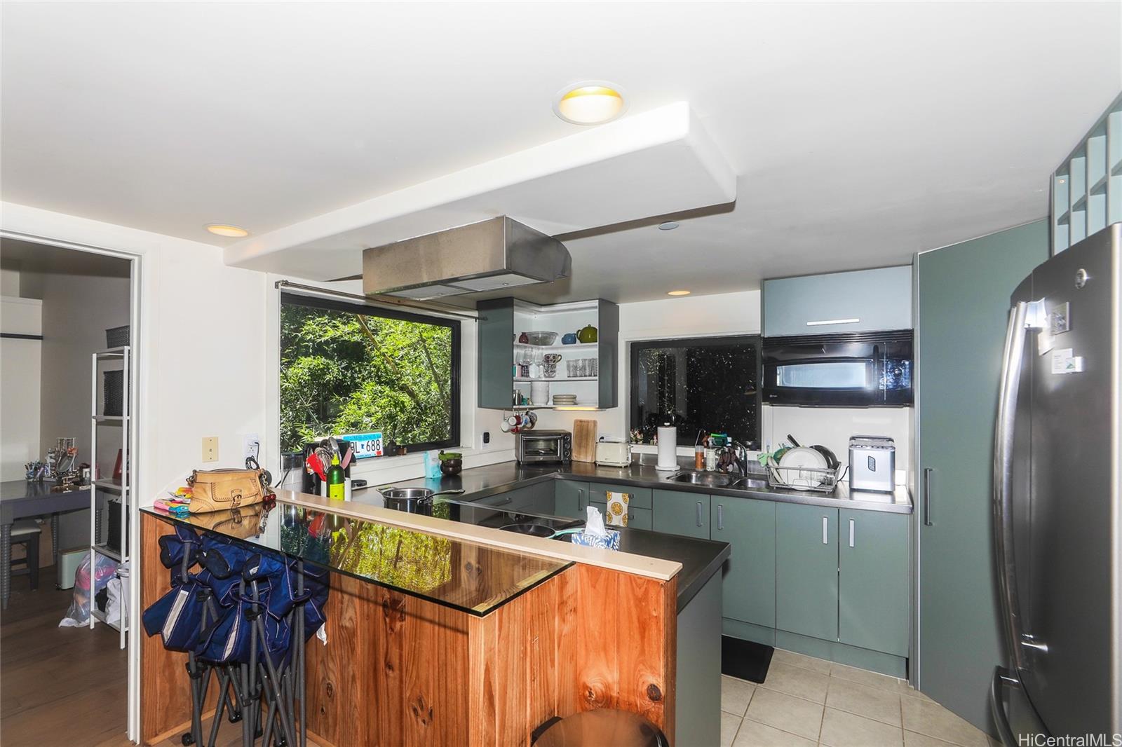 3702 Old Pali Road Honolulu, HI 96817 - Photo 13 of 25 a kitchen with stainless steel appliances granite countertop a refrigerator a sink dishwasher a dining table and chairs with wooden floor