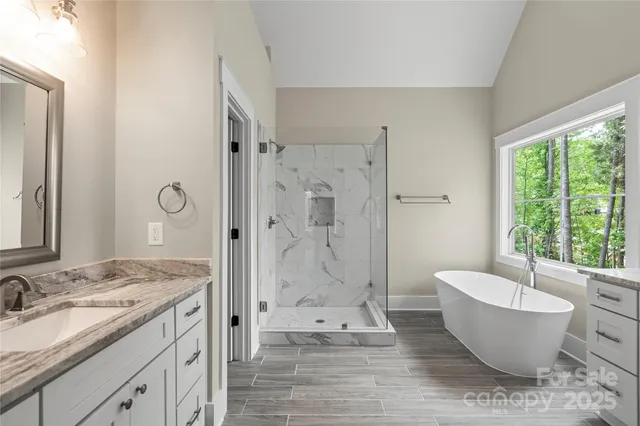 a spacious bathroom with a granite countertop tub sink a shower and a mirror