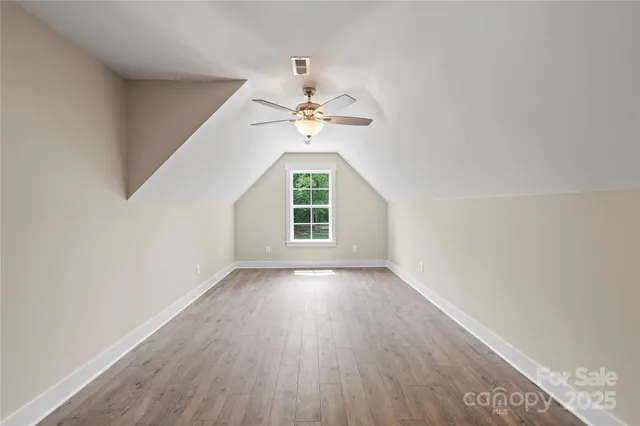 an empty room with wooden floor chandelier fan and windows