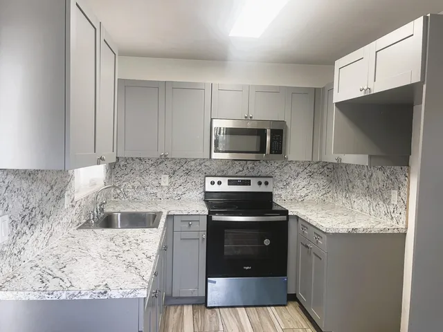 a kitchen with stainless steel appliances granite countertop a sink stove and microwave