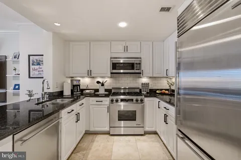 a kitchen with stainless steel appliances granite countertop a stove a sink and a refrigerator