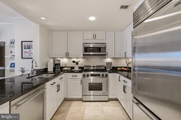 a kitchen with stainless steel appliances granite countertop a stove a sink and a refrigerator