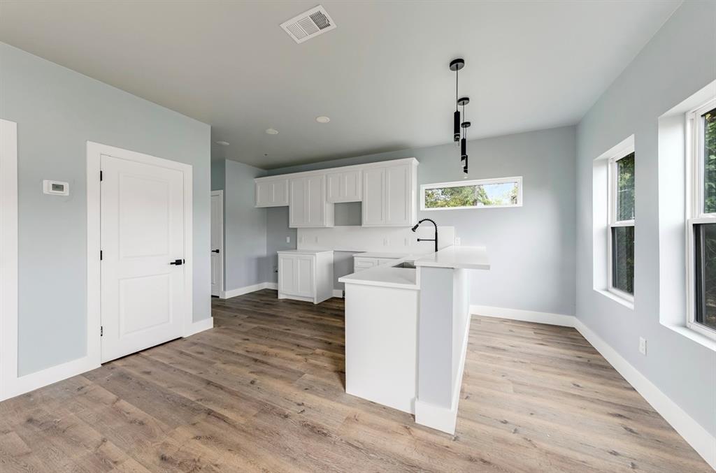 1113 East Oleander Street Fort Worth, TX 76104 - Photo 12 of 39 Kitchen featuring a peninsula, white cabinetry, light wood-type flooring, and pendant lighting