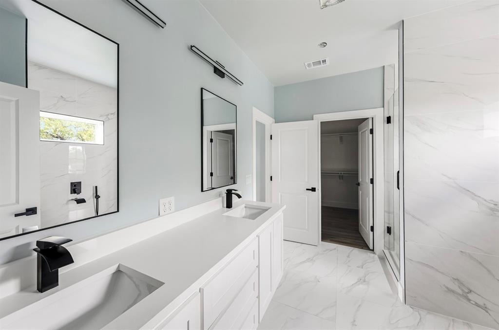 1113 East Oleander Street Fort Worth, TX 76104 - Photo 35 of 39 Bathroom with a spacious closet, double vanity, light marble finish flooring, a wall unit AC, and a marble finish shower