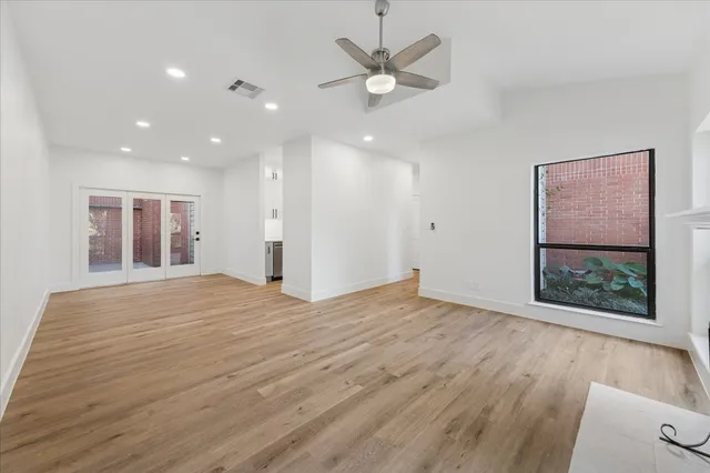 a view of an empty room with a window and a kitchen